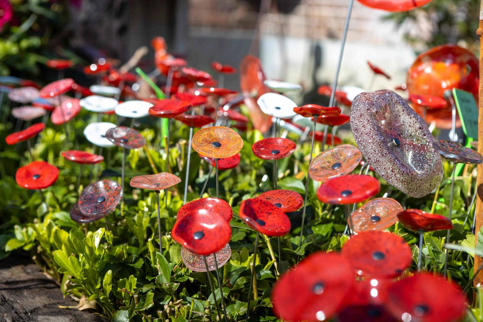 Rode glazen klaprozen op stokken in de tuin