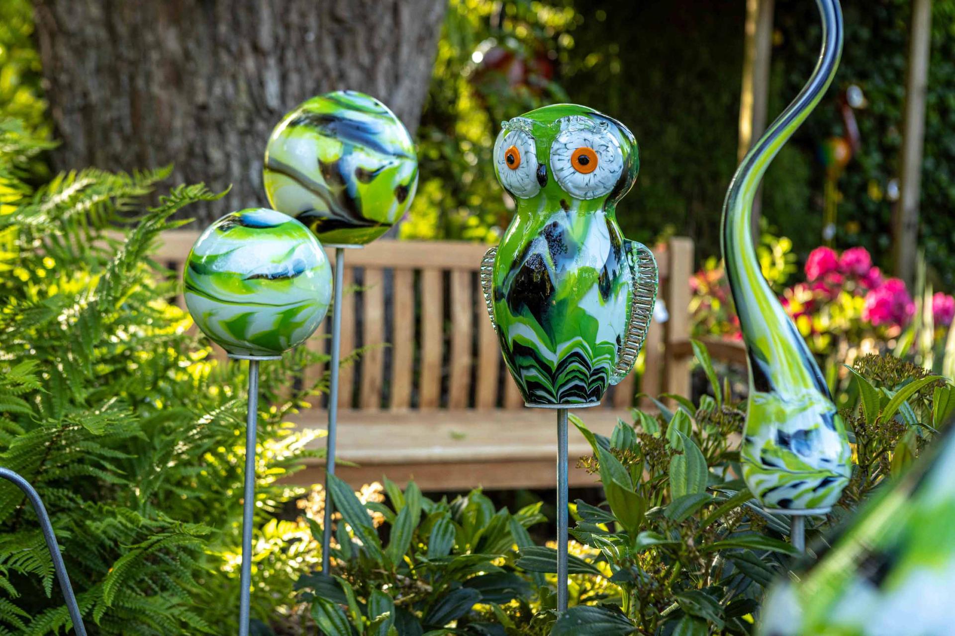 Glaskunst uil en bollen op stokken in de tuin